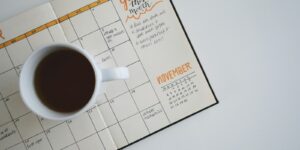 white ceramic mug with coffee on top of a planner